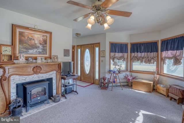 carpeted living room with ceiling fan and a wood stove