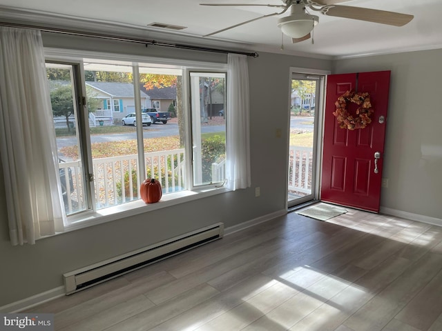 entrance foyer featuring a baseboard radiator, light hardwood / wood-style floors, ornamental molding, and a healthy amount of sunlight