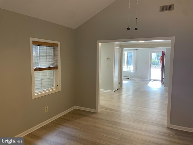 interior space with a baseboard radiator, light wood-type flooring, and vaulted ceiling