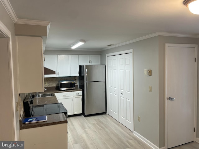 kitchen with backsplash, crown molding, white cabinetry, appliances with stainless steel finishes, and light hardwood / wood-style floors