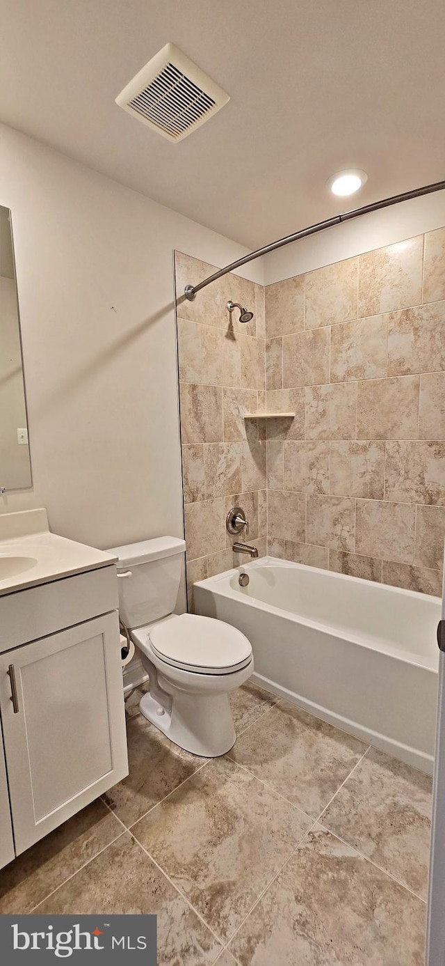 full bathroom featuring vanity, tiled shower / bath, and toilet