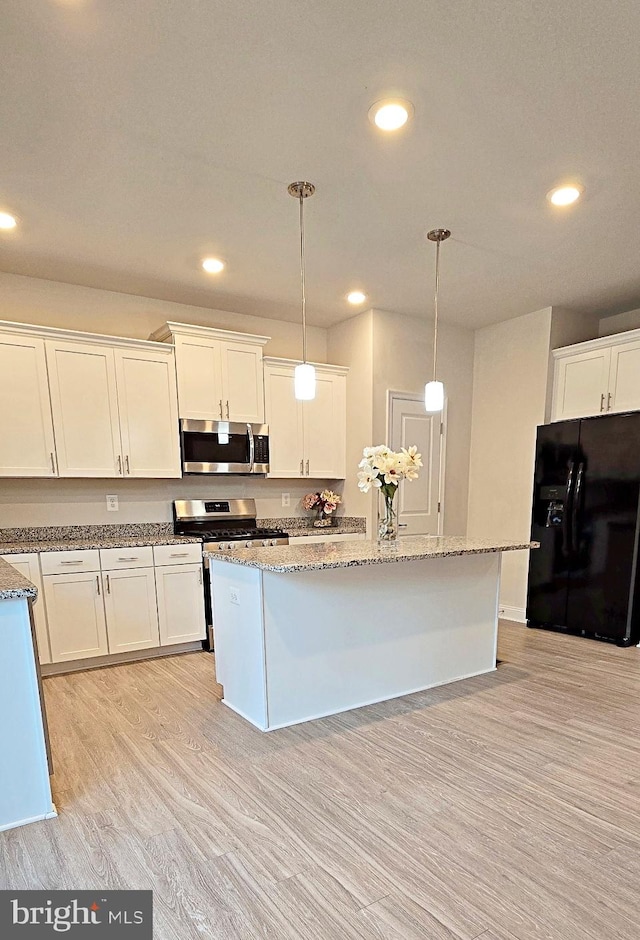 kitchen featuring white cabinetry, appliances with stainless steel finishes, decorative light fixtures, an island with sink, and light hardwood / wood-style flooring