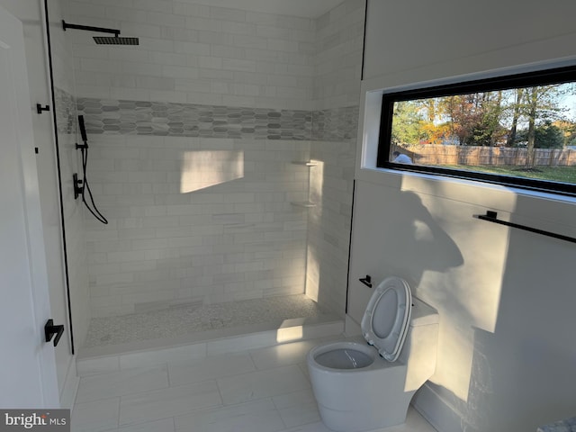 bathroom with toilet, tile patterned flooring, and tiled shower