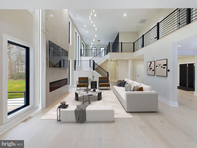 5005 Ravensworth Rd, Annandale, VA 22003 - living room featuring a towering ceiling, stairs, light wood-style flooring, a fireplace, and baseboards
