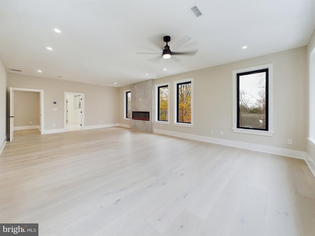 unfurnished living room with light hardwood / wood-style floors, ceiling fan, and a premium fireplace