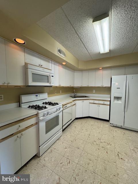 kitchen featuring white cabinetry, white appliances, and sink