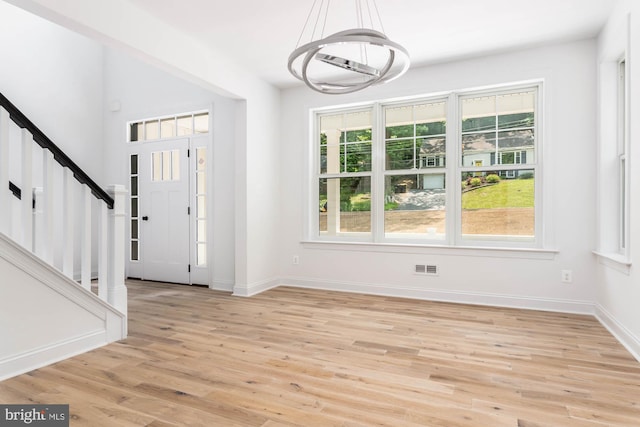 entryway with light hardwood / wood-style flooring and a notable chandelier