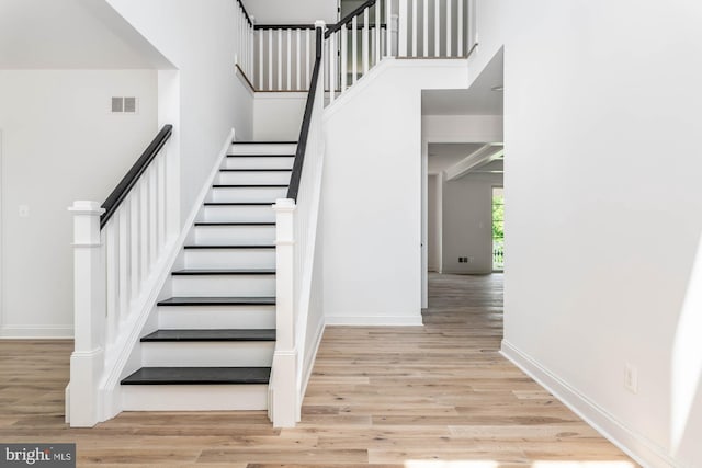 stairs with hardwood / wood-style floors and a high ceiling