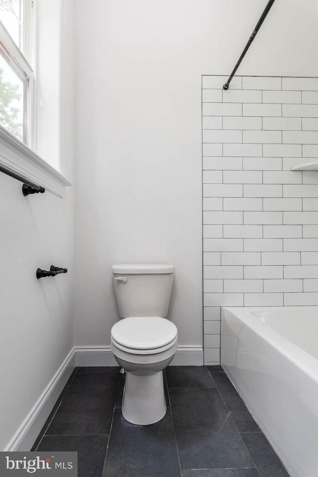 bathroom with toilet, tile patterned floors, and tiled shower / bath