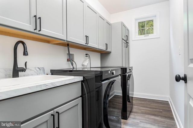 clothes washing area with sink, wood-type flooring, separate washer and dryer, and cabinets