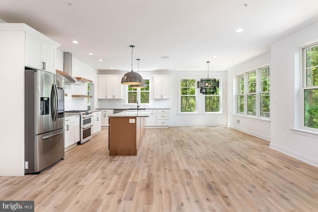 kitchen featuring white cabinetry, stainless steel appliances, a kitchen island, and hanging light fixtures