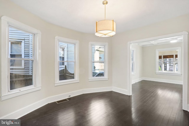 spare room featuring a wealth of natural light and dark hardwood / wood-style floors