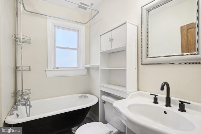 bathroom featuring toilet, a tub to relax in, and sink