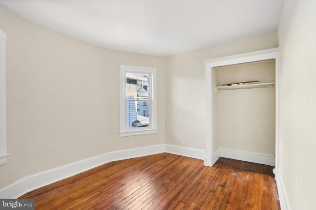 unfurnished bedroom with a closet and dark hardwood / wood-style flooring