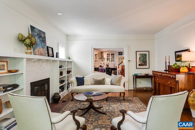 living room featuring a brick fireplace and dark hardwood / wood-style flooring