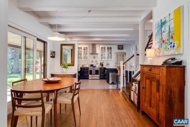 dining space with beamed ceiling and light hardwood / wood-style flooring