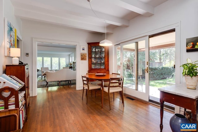 dining space with hardwood / wood-style flooring and beamed ceiling