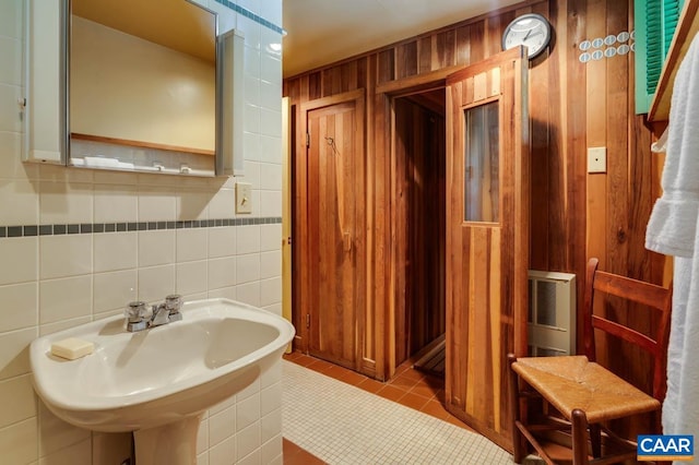 bathroom with wood walls, tile walls, sink, and tile patterned flooring