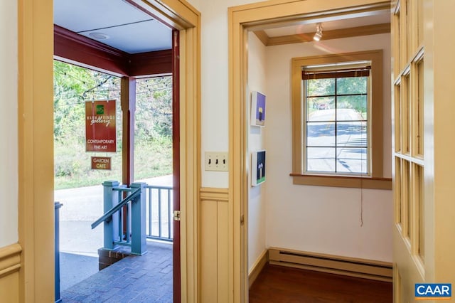 doorway with a baseboard radiator, ornamental molding, and dark hardwood / wood-style floors