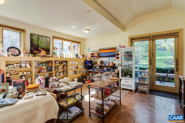 interior space with lofted ceiling, dark parquet floors, and a healthy amount of sunlight