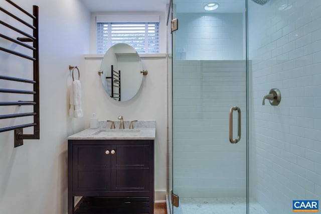 bathroom featuring a shower with door, vanity, and radiator