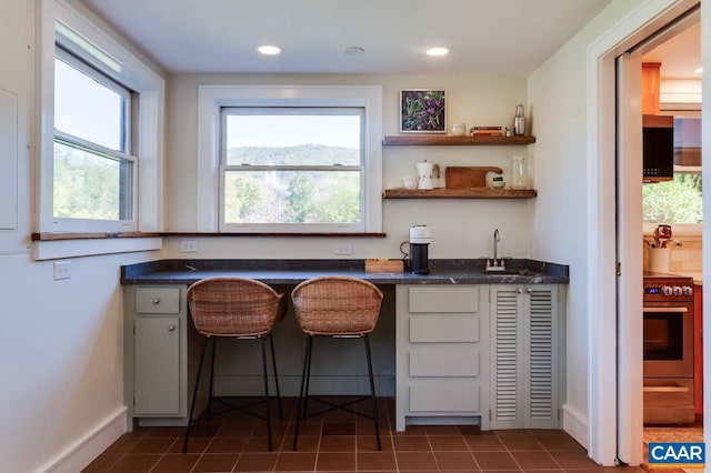 bar featuring dark tile patterned floors, sink, and stainless steel range with electric stovetop