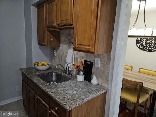 kitchen with tasteful backsplash, light stone counters, sink, and tile patterned flooring