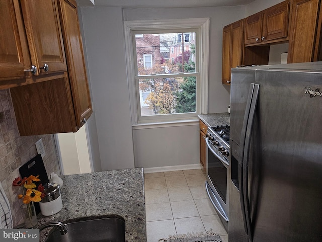 kitchen with light stone countertops, appliances with stainless steel finishes, decorative backsplash, sink, and light tile patterned floors