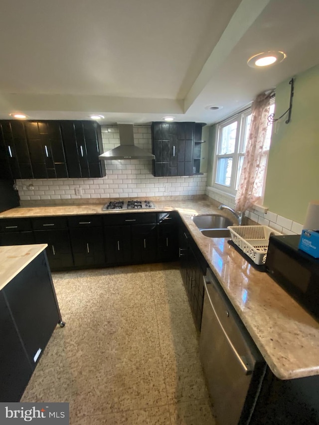 kitchen featuring stainless steel appliances, wall chimney exhaust hood, sink, and decorative backsplash