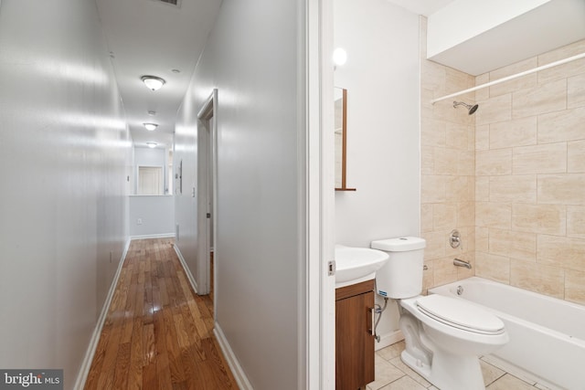 full bathroom featuring toilet, tiled shower / bath combo, vanity, and wood-type flooring