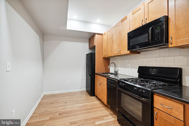 kitchen with light hardwood / wood-style floors, tasteful backsplash, black appliances, and sink