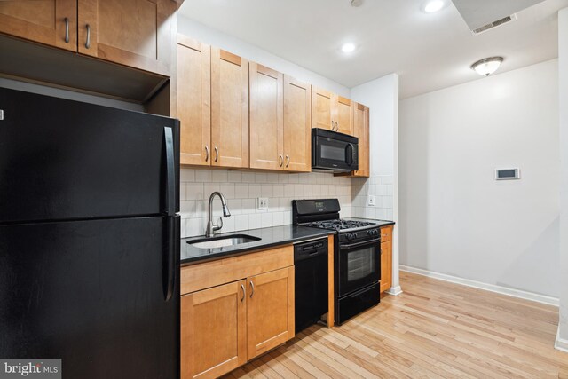 kitchen with light hardwood / wood-style floors, decorative backsplash, black appliances, and sink