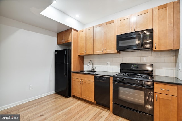 kitchen featuring tasteful backsplash, black appliances, sink, and light wood-type flooring