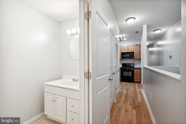 bathroom featuring hardwood / wood-style floors, vanity, and decorative backsplash