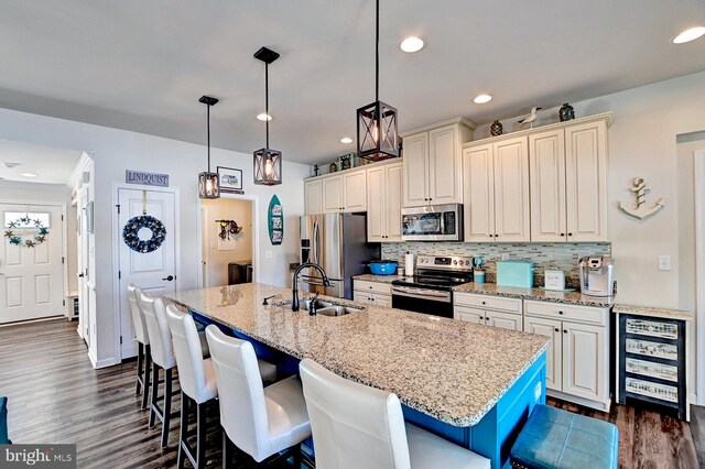 kitchen featuring appliances with stainless steel finishes, sink, pendant lighting, a breakfast bar, and a kitchen island with sink