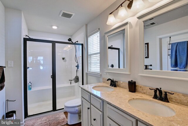 bathroom featuring toilet, an enclosed shower, and vanity