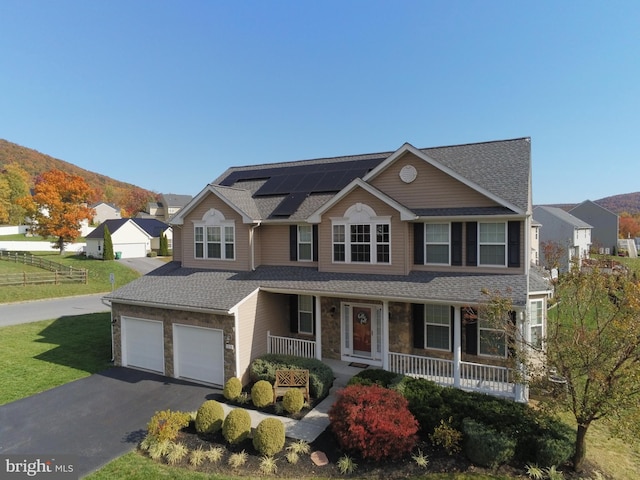 view of front facade with a garage, a front yard, solar panels, and a porch