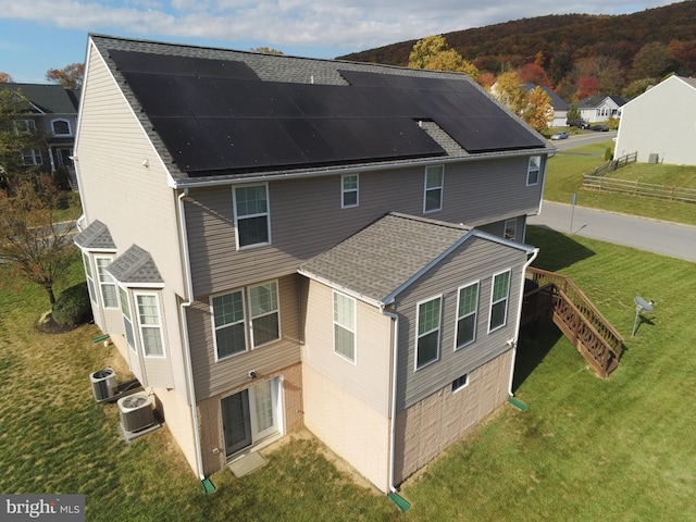 rear view of property featuring cooling unit and a lawn