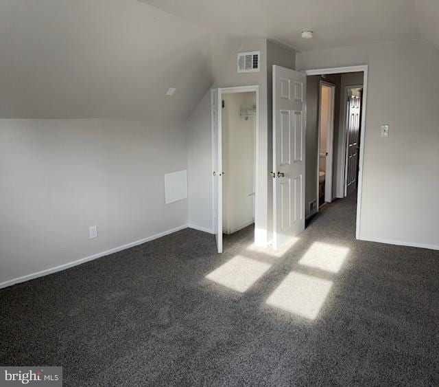 additional living space with dark carpet and lofted ceiling