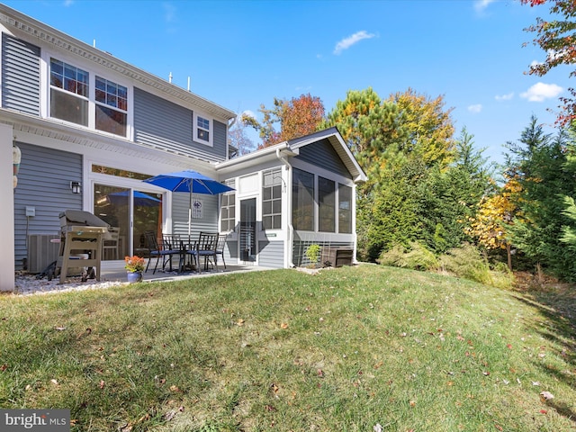 back of house featuring a sunroom, a patio, and a lawn