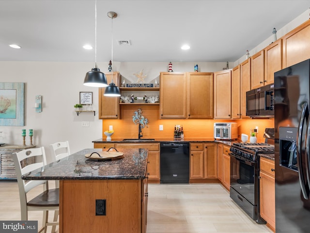 kitchen with a center island, black appliances, a kitchen breakfast bar, sink, and decorative light fixtures