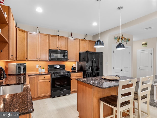 kitchen with sink, tasteful backsplash, decorative light fixtures, a kitchen island, and black appliances