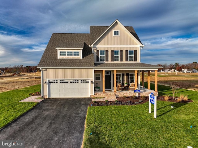 craftsman-style house featuring covered porch, a garage, and a front yard