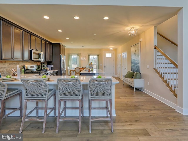 kitchen featuring dark brown cabinetry, kitchen peninsula, appliances with stainless steel finishes, and decorative light fixtures