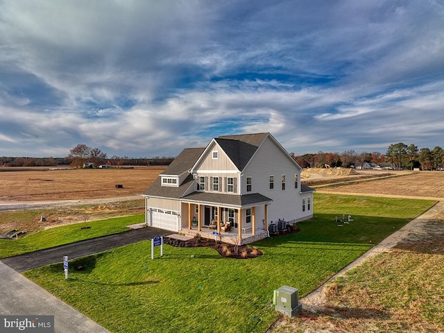 view of front of home with covered porch, a garage, a rural view, and a front yard