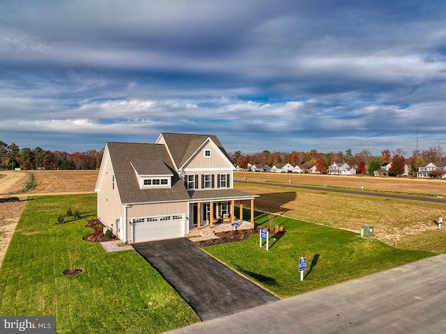 view of front of house featuring a garage, a front lawn, and covered porch