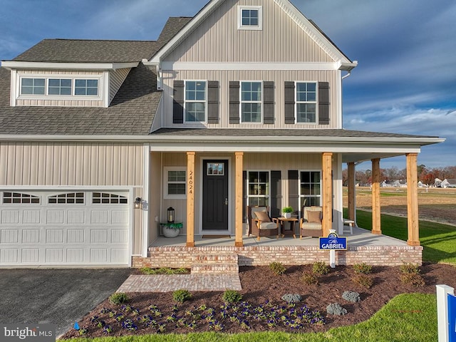 view of front of property featuring a garage, a front lawn, and a porch