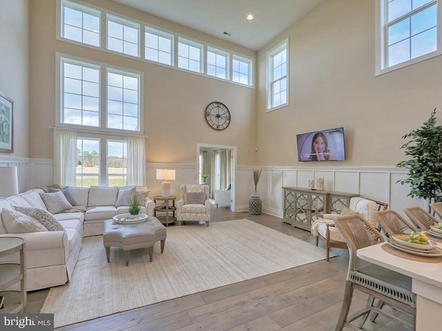 living room with light hardwood / wood-style flooring, plenty of natural light, and a towering ceiling