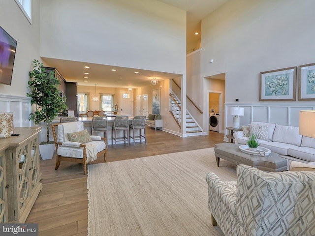 living room with light hardwood / wood-style flooring, a high ceiling, and washer / dryer