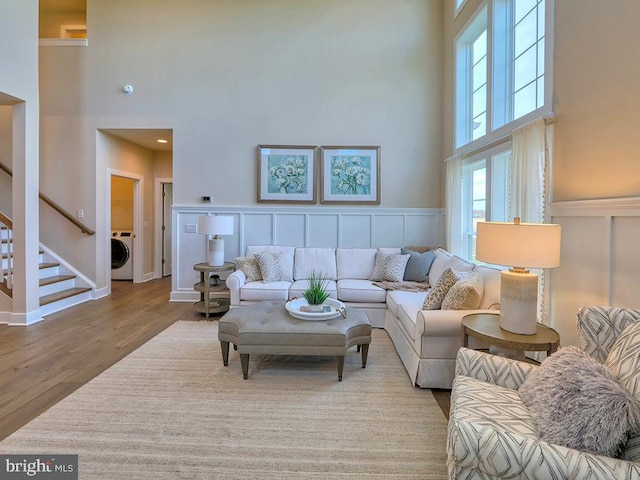 living room featuring a towering ceiling, washer / dryer, and light wood-type flooring